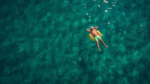 Person floating on a yellow inflatable in a clear ocean